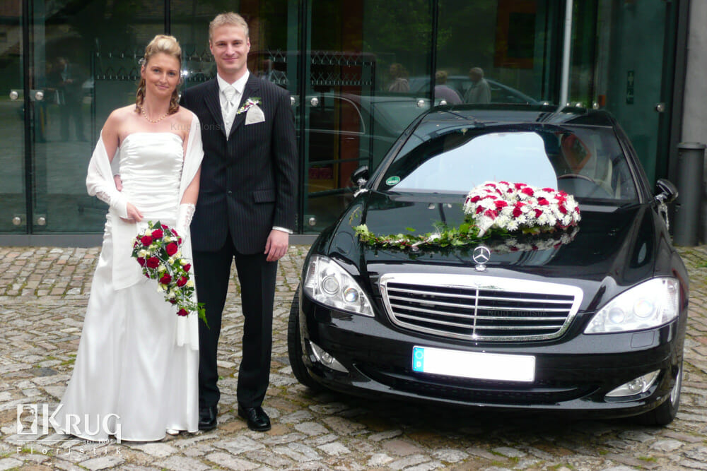 Brautpaar mit Brautstrauß und Autoherz für Hochzeit rot-weiß mit Rosen