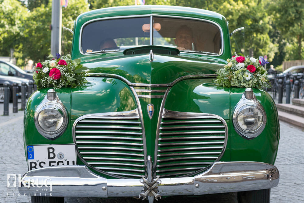 grüner Oldtimer mit Blumenschmuck zur Hochzeit